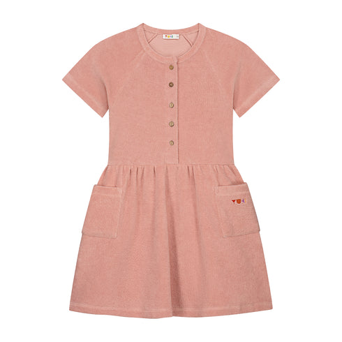 The Yuki kidswear Terry Dress Anna in Blossom Pink features short sleeves, front buttons, two large front pockets with a small YOU logo, a gathered waist, and is made from soft organic cotton for all-day comfort.